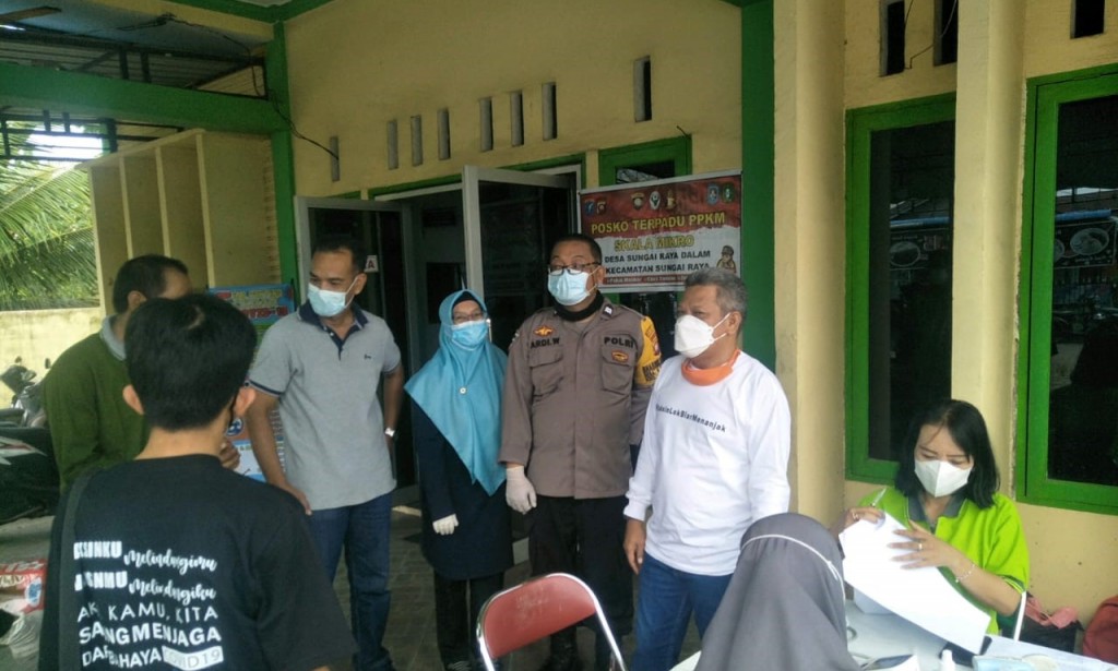 BHABINKAMTIBMAS DESA SUNGAI RAYA DALAM KAWAL VAKSINASI DI AULA KANTOR DESA SUNGAI RAYA DALAM
