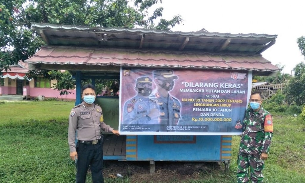 Ajak warga tidak membakat hutan dan lahan, Bhabinkamtibmas Polsek Sungai Raya bersama Babinsa Pasang Spanduk Karhutla